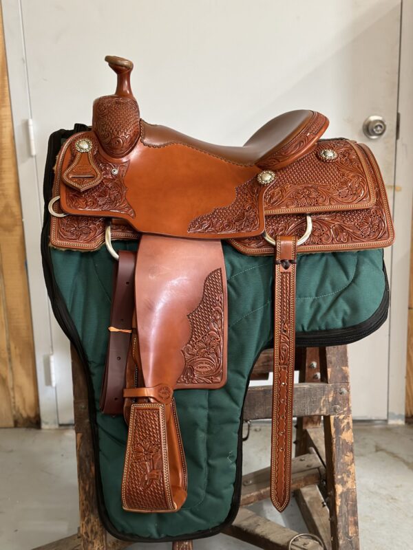 A saddle is sitting on the ground in front of a door.