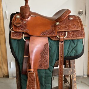 A saddle is sitting on the ground in front of a door.