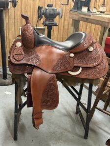 A saddle that is sitting on top of a wooden table.