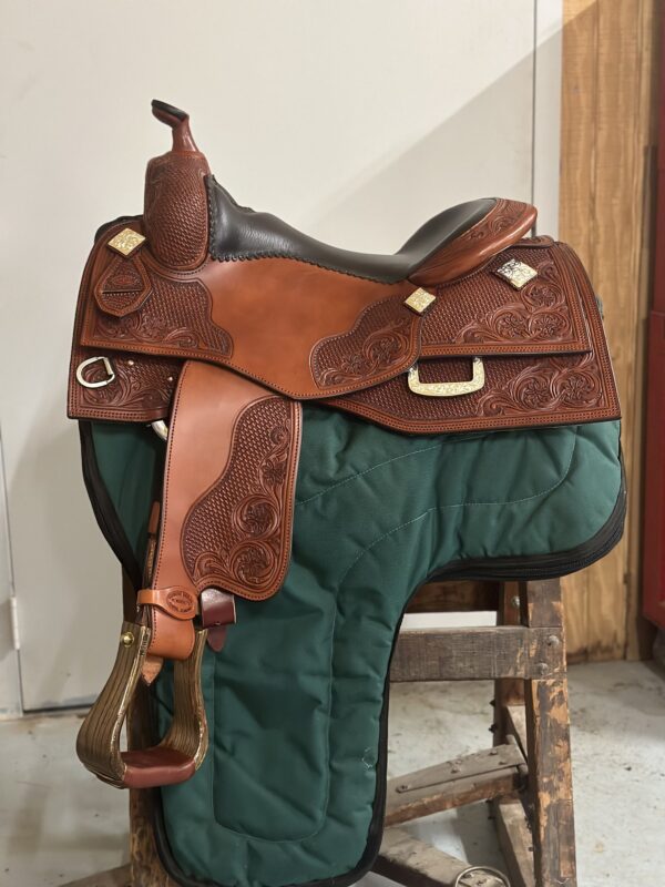 A saddle is sitting on the ground in front of a wall.