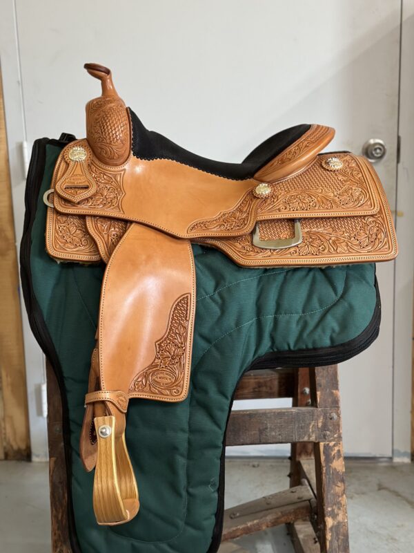 A saddle is sitting on the ground in front of a door.