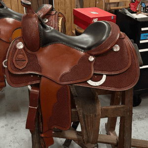 A saddle is sitting on top of a wooden stool.