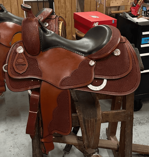 A saddle is sitting on top of a wooden stool.