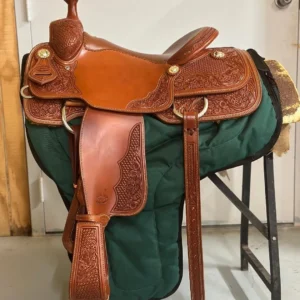 A saddle is sitting on the ground in front of a door.