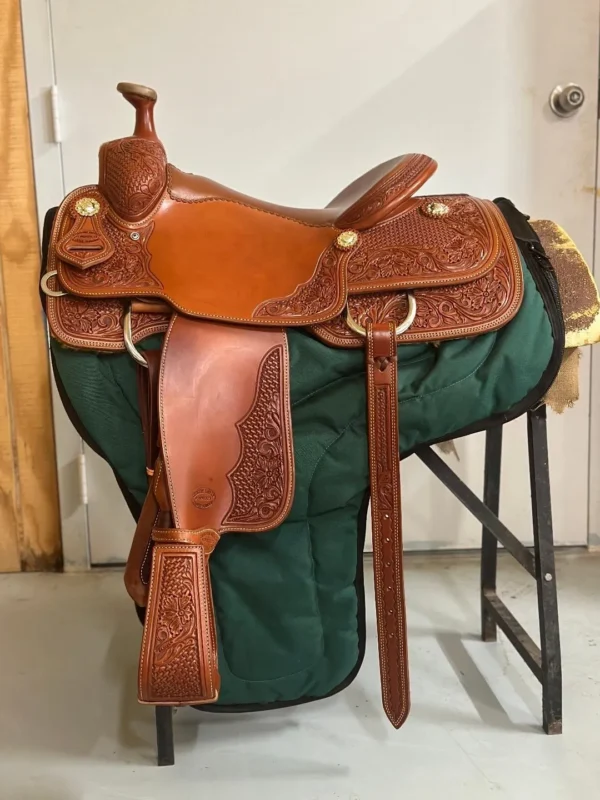 A saddle is sitting on the ground in front of a door.